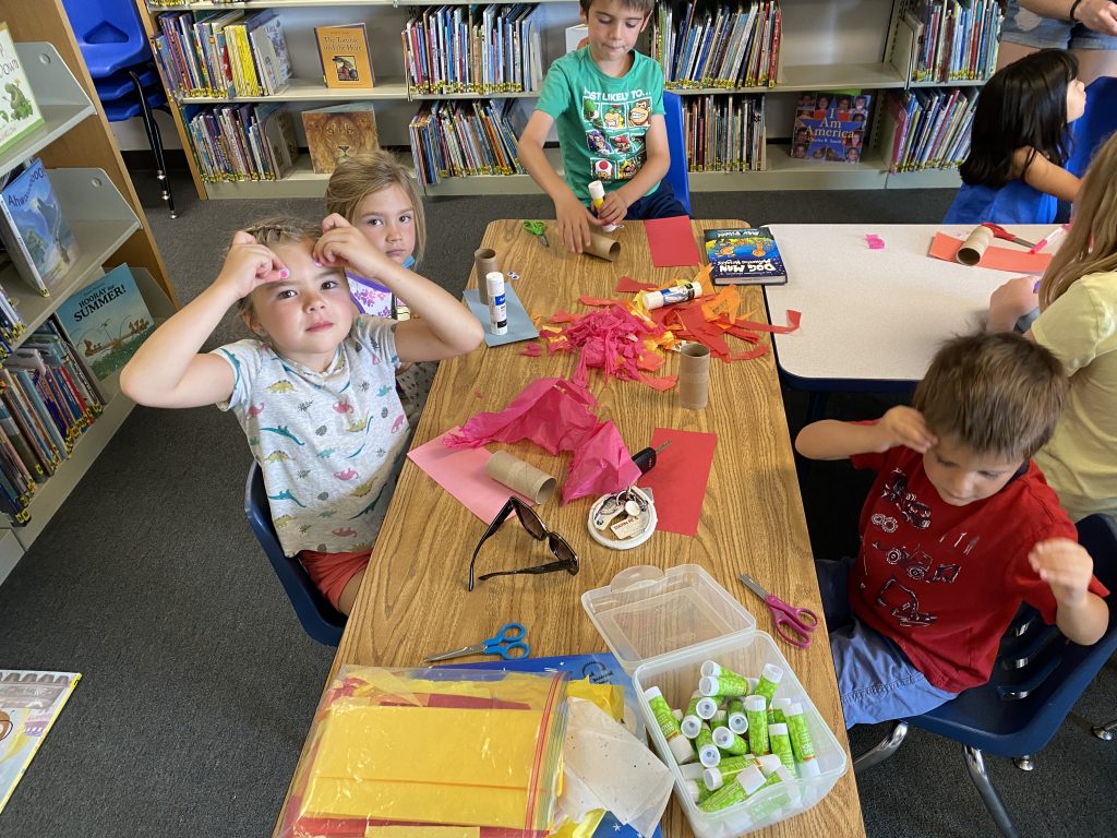 Photo of kids putting goggle eyes on their foreheads, during Story Time, at the Elizabeth Library.